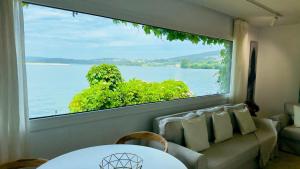 a living room with a large window looking out at the water at Cabanas da Auga A in A Telleira