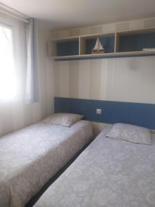 a bedroom with two beds and a window and shelves at Mobil home YANN in Sainte-Croix-de-Verdon