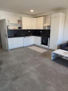 a kitchen with white cabinets and a tile floor at Apartmán na Břehách in Veselí nad Moravou
