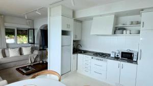 a small kitchen with white cabinets and a couch at Cabanas da Auga B in Casas Novas