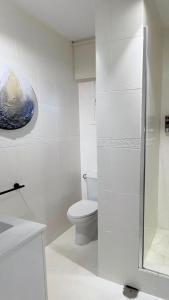 a white bathroom with a toilet and a glass shower at Cabanas da Auga B in Casas Novas