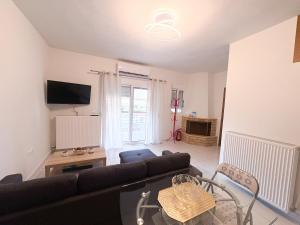 a living room with a couch and a tv at Alexandros House in Néa Tríglia