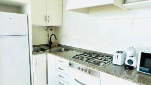 a white kitchen with a sink and a stove at Cabanas da Auga B in Casas Novas +19 photos