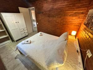 a bedroom with a bed and a brick wall at Casita siempre verde in Los Hornillos +26 photos