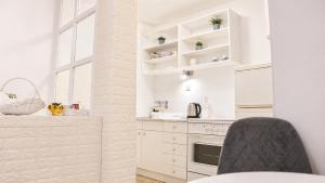 a kitchen with white cabinets and a black chair at Apartman San in Mostar