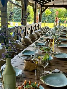 a long wooden table with plates of food and wine glasses at Kosa Śpiew Joga i Spa in Kosewo