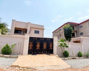 a house with a black gate and a building at The Crest at Oyarifa in Oyarifa