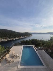 a swimming pool with chairs and a view of the water at Dream View Villa in Jadranovo