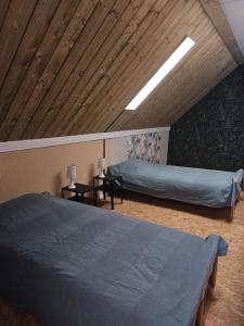 a bedroom with two beds and a wooden ceiling at Les Marronniers Roses in Châteaulin