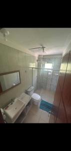 a bathroom with a sink and a toilet and a mirror at COBERTURA Duplex 302,vista d Mar e piscina in Piúma