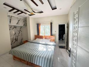 a bedroom with a bed and a ceiling fan at Ember Guest House in Abbottabad