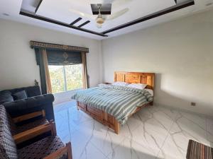 a bedroom with a bed and a couch and a window at Ember Guest House in Abbottabad +10 photos