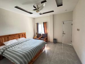 a bedroom with a bed and a ceiling fan at Ember Guest House in Abbottabad
