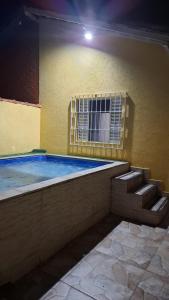 a swimming pool with a window and stairs next to a building at Casa com churrasqueira e piscina in Itanhaém