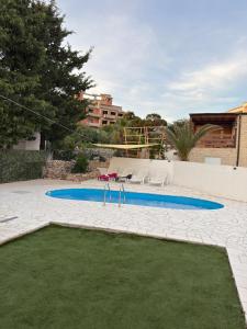 a swimming pool in a yard with some grass at Villa Adria in Novalja