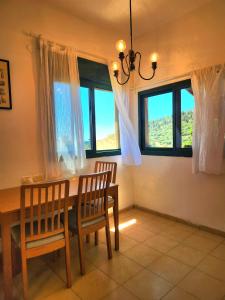 a dining room with a table and chairs and windows at קצה ההר in Amirim