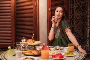 a woman sitting at a table drinking from a glass at Riad El Maâti in Rabat