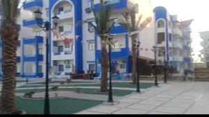 a large building with palm trees in front of it at اوسس مارينا in `Ezbet Bûgti
