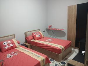 two beds in a room with red sheets at اوسس مارينا in `Ezbet Bûgti