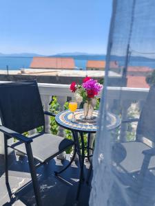a table with a vase of flowers and a drink on a balcony at ĆOSIĆ APARTMANI IGRANE in Igrane