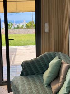 a couch with pillows sitting in front of a sliding glass door at VILLAGE CLUB 27 in Nea Fokea