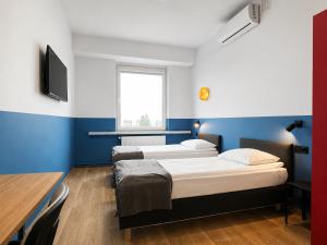 two beds in a room with blue walls at Pokoje & Bistro Mielec in Mielec