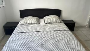 a bed with a black headboard and two pillows at CHAMBRE Calme et Bien située in Le Lamentin +3 photos
