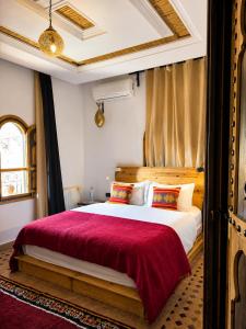a bedroom with a large bed with a red blanket at Dar Rihana Dadès in Aït Idaïr