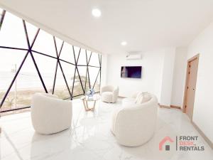 a living room with white chairs and large windows at Beachfront Escape Pool Hot Tub and Fire pit in Montañita