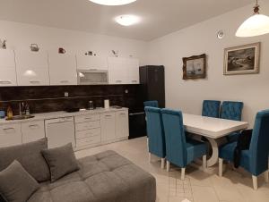 a kitchen with a table and blue chairs and a couch at Lustica-Apartment Dora3 in Herceg-Novi