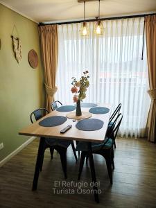 a dining room table with chairs and a vase with flowers at Departamento El refugio in Osorno