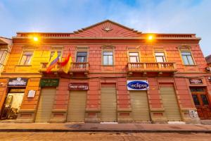 a colorful building with two flags in front of it at Hotel Majestic 1 Centro Histórico Cuenca in Cuenca