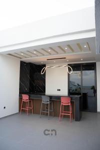 a bar with three pink stools and a white screen at Villa CICAS in Cotonou