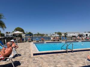 a group of people sitting in chairs by a swimming pool at Tami Beach Resort Rental in Fort Myers Beach
