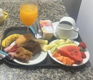 a tray with two plates of food and a glass of orange juice at Motel Blue Star II in Campo Mourão