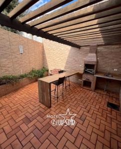 a patio with a wooden table and a grill at Motel Blue Star II in Campo Mourão