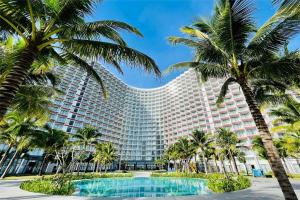 a large building with palm trees in front of it at Hanna Seaview Stella - The Arena Resort in Cam Ranh International Airport