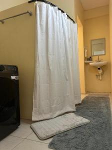 a white shower curtain in a bathroom with a sink at Hibiscus Apt 1 in Corinthe