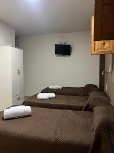 two beds in a room with a tv on the wall at Casa UNO in San Rafael