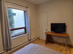 a bedroom with a bed and a television and a window at Martin's apartment in Saguenay