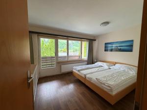 a bedroom with a bed and a large window at Schlossli-Le Petit Chateau in Leukerbad