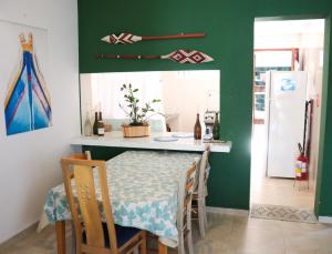 a dining room with a table and a green wall at Caeté Suítes in Ubatuba