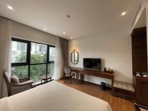a bedroom with a bed and a desk and a television at Mariha Hotel Ninh Bình in Ða Gia
