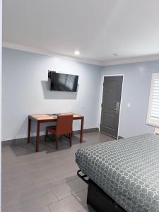 a bedroom with a bed and a desk and a television at Coronado Motel in Long Beach +10 photos