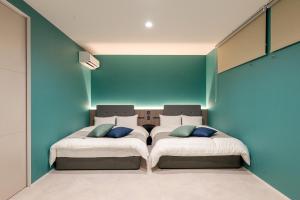 two beds in a room with blue walls at Universal front villa Sanrriott in Osaka +62 photos