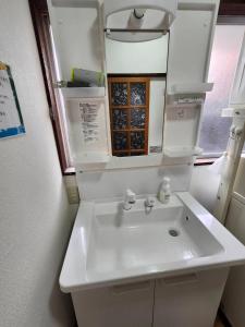 a bathroom with a white sink and a mirror at Guesthouse Face to Face in Fujinomiya