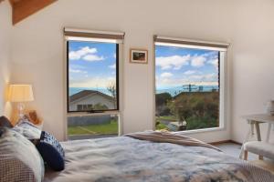 a bedroom with a bed and two large windows at Seven Views in Clifton Springs