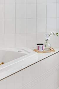 a white bathroom with a sink and a vase of flowers at Seven Views in Clifton Springs +26 photos
