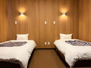 two beds in a room with two lights on the wall at みずほガーデンロッジ in Kyotamba +24 photos