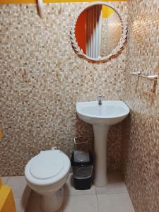 a bathroom with a sink and a toilet and a mirror at Mi Hábitat Lambaré - Habitaciones con Baño Privado, Cocina y Comedor equipados con electrodomésticos, con Quincho al Aire Libre in Asunción +16 photos